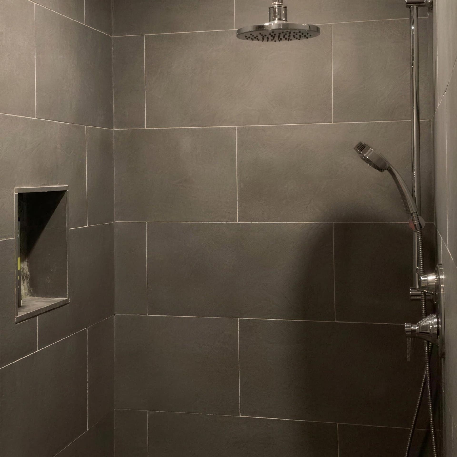 A tiled walk-in shower by The Laughing Heart Plumbing Company